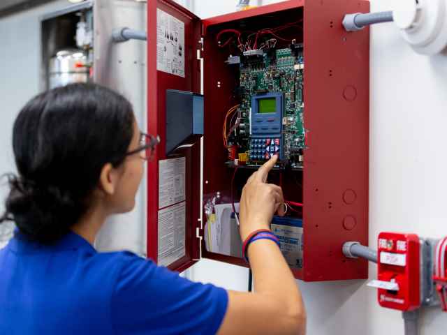 A student works on a fire sprinkler system panel.