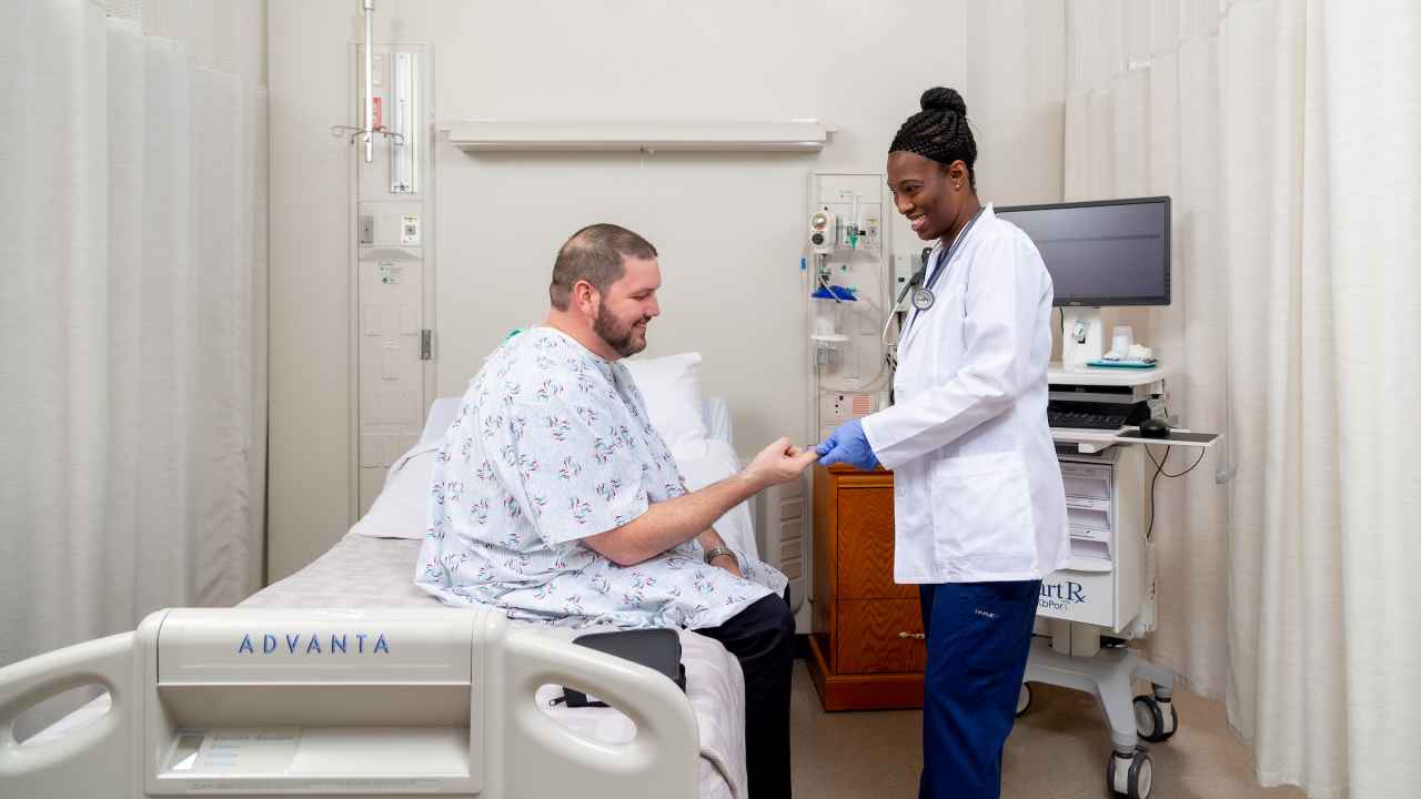 A nurse helps a patient sitting on a hospital bed. A nurse helps a patient sitting on a hospital bed.