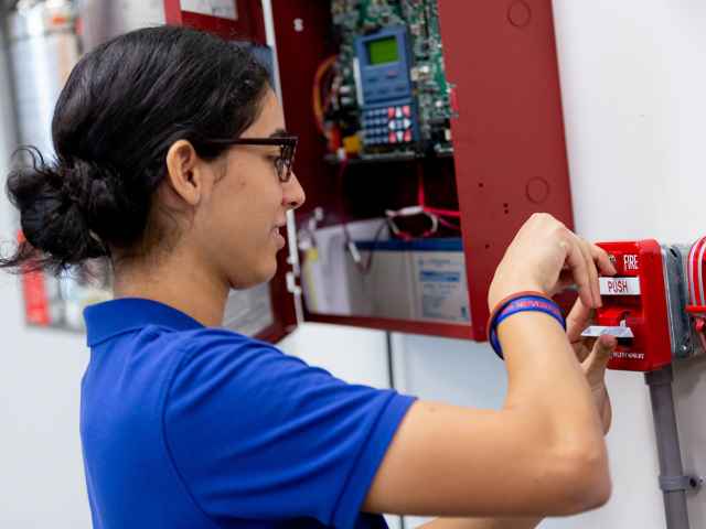 A student works on a fire sprinkler