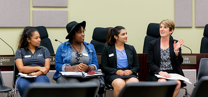 Dr. Georgia Lorenz participates in a small group discussion with students in a meeting room.