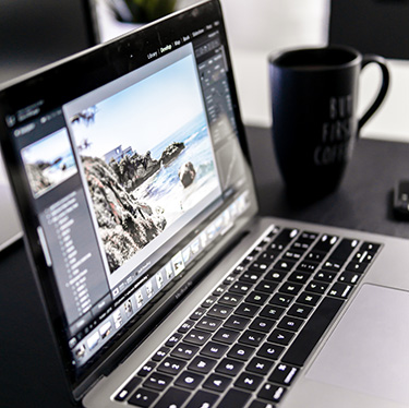 Black and gray laptop on a black tabletop with a black coffee cup in the background.
