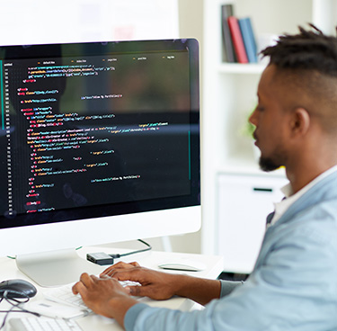 A web developer sitting at a desk, working on a computer and coding