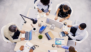 A group of people working together on computers at a table.