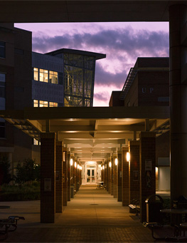 Campus building illuminated at dusk with a colorful fountain in the foreground.