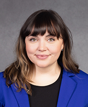 Laura headshot, woman with brown hair, bangs and a blue jacket