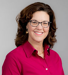 A woman with glasses wearing a red shirt and smiling.