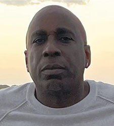 Close-up of a man outdoors as the sun sets behind him.