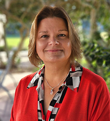 Person wearing a red sweater and patterned blouse standing outdoors.