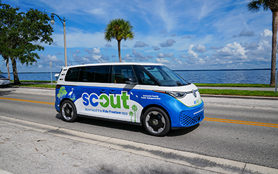 A Scout VW van drives down the road on a sunny day.