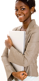 A women, wearing a beige suit, holding a laptop and smiling at the camera against a white background