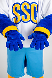 A person standing in the Rally suit and showing the royal blue gloves.